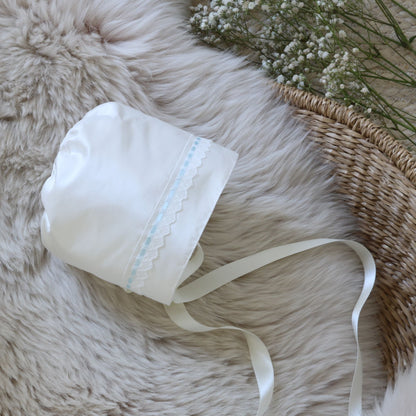 Ivory bonnet on a sheepskin rug and basket. lowers in the corner
