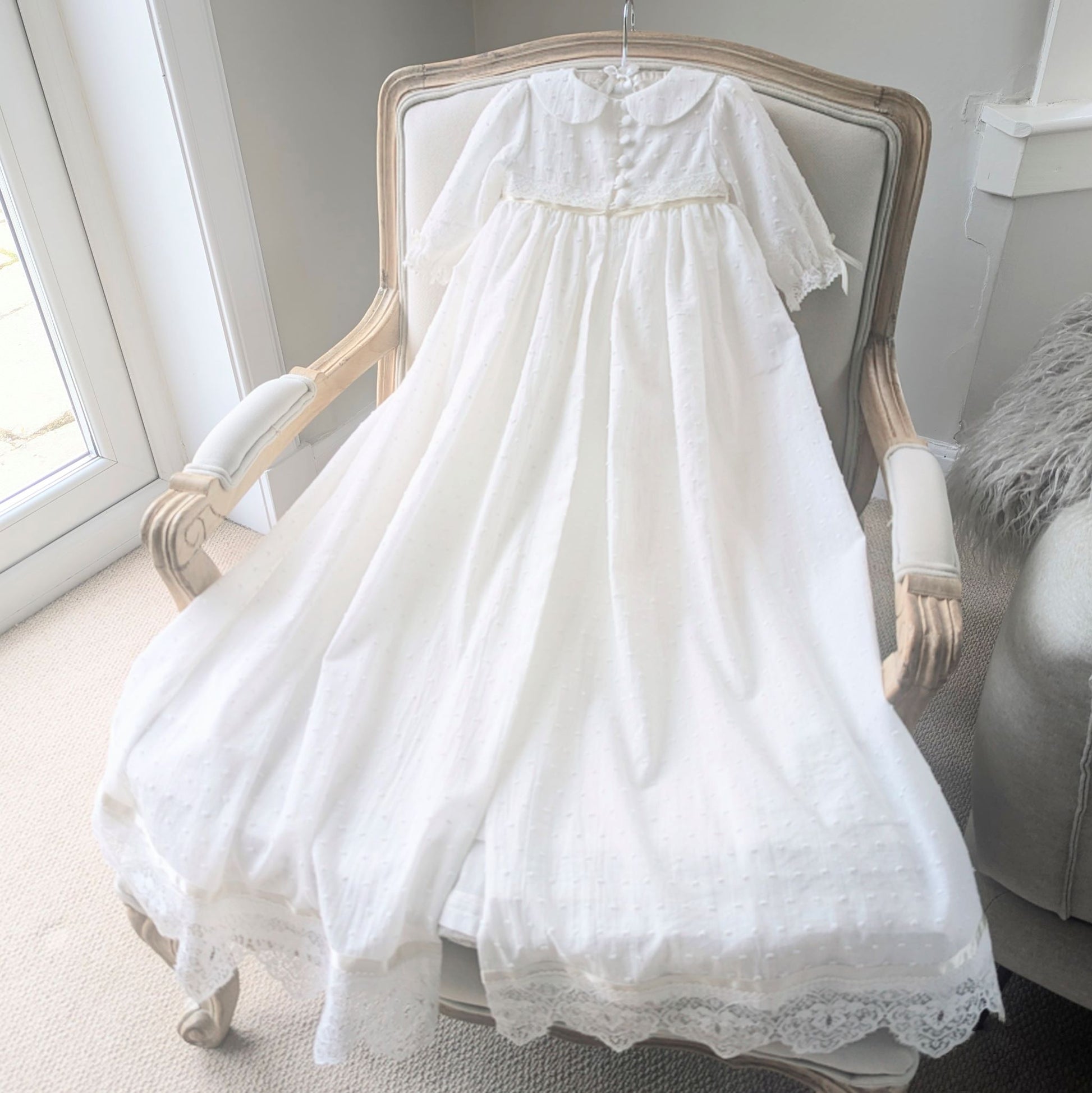Full-length back view of the Isabella christening gown, demonstrating the traditional open-back skirt design for elegant draping over the arm