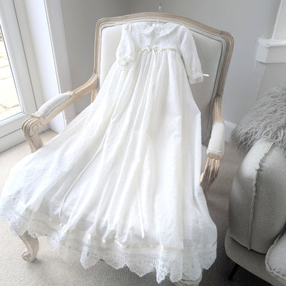 The Isabella luxury couture baptism gown displayed in full length, showing the elegant drape of the plumeti cotton fabric.