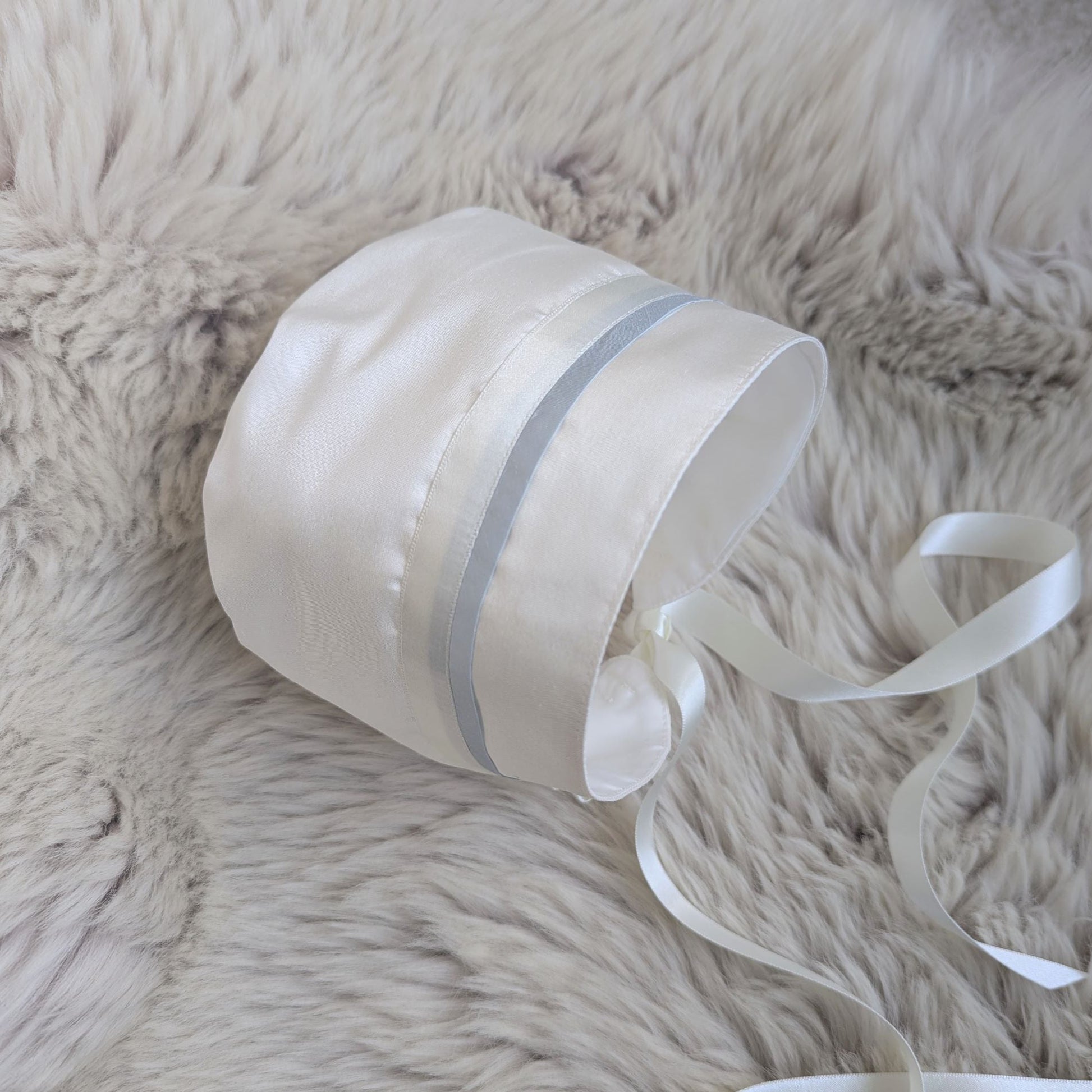 Baby boy ivory silk baptism bonnet featuring a delicate light blue trim and satin ribbon ties