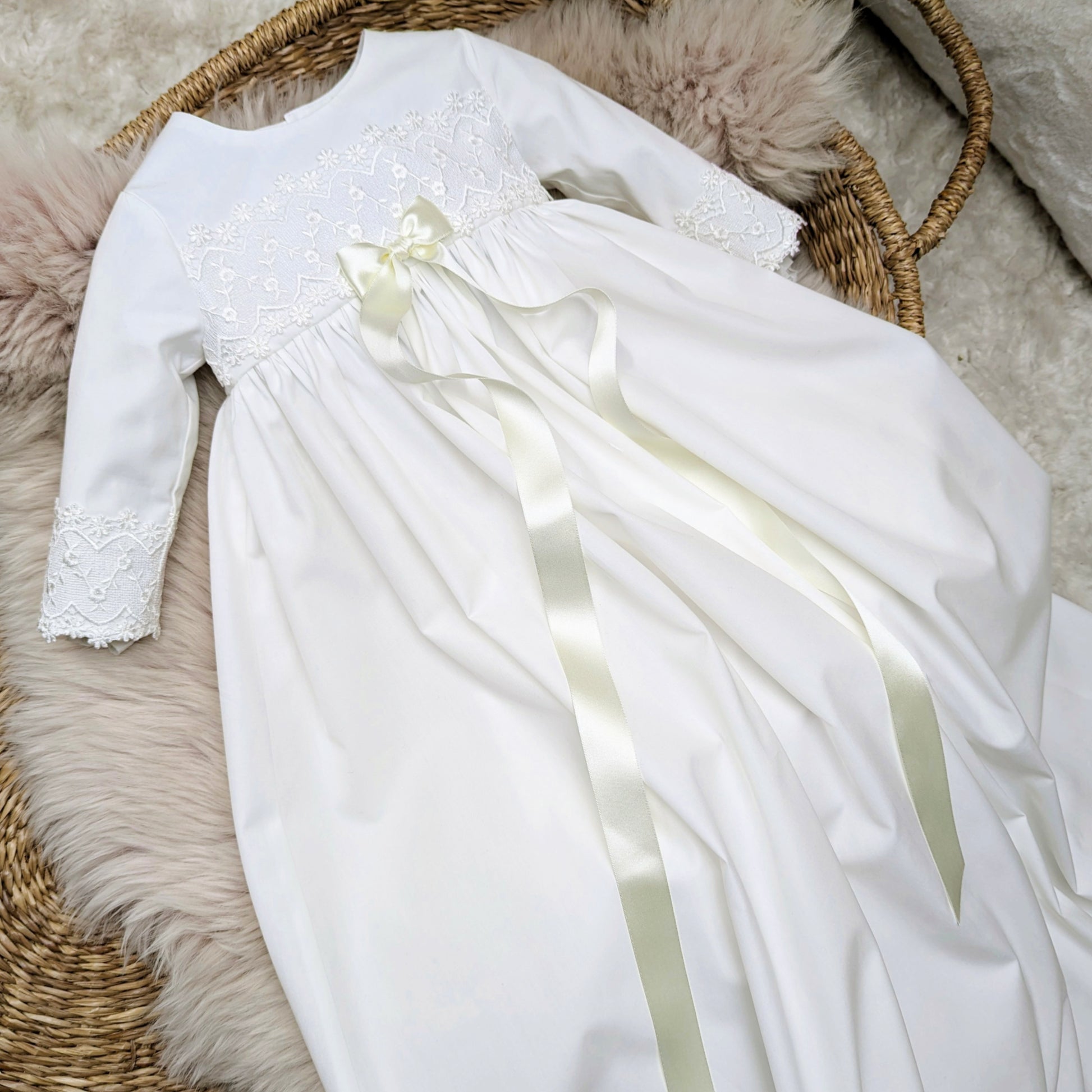 Lana Ivory long christening gown with long sleeves and a bow showing mainly the bodice with the long flowing ribbons 