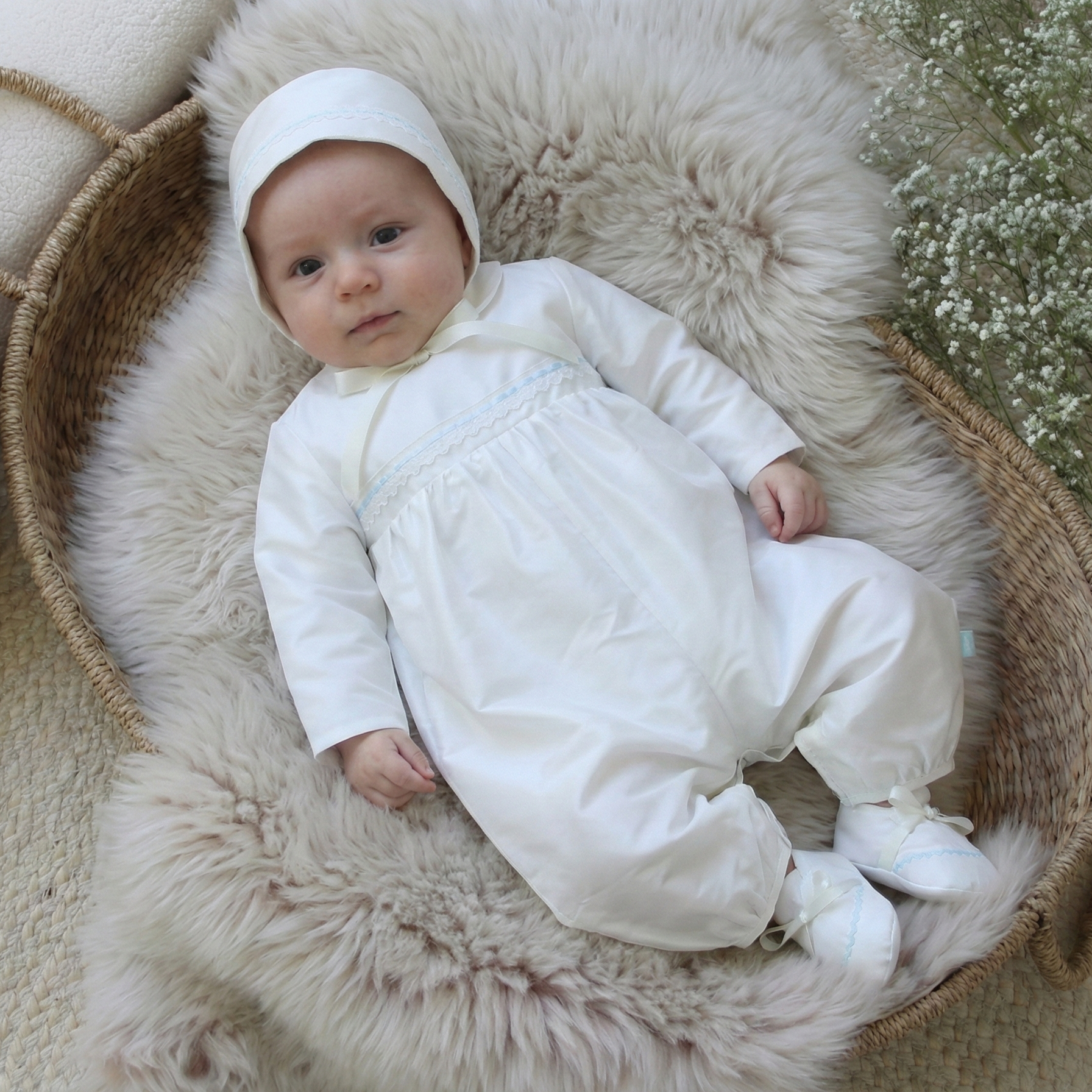 baby boy wearing the Oliver christening outfit whilst lying in a basket