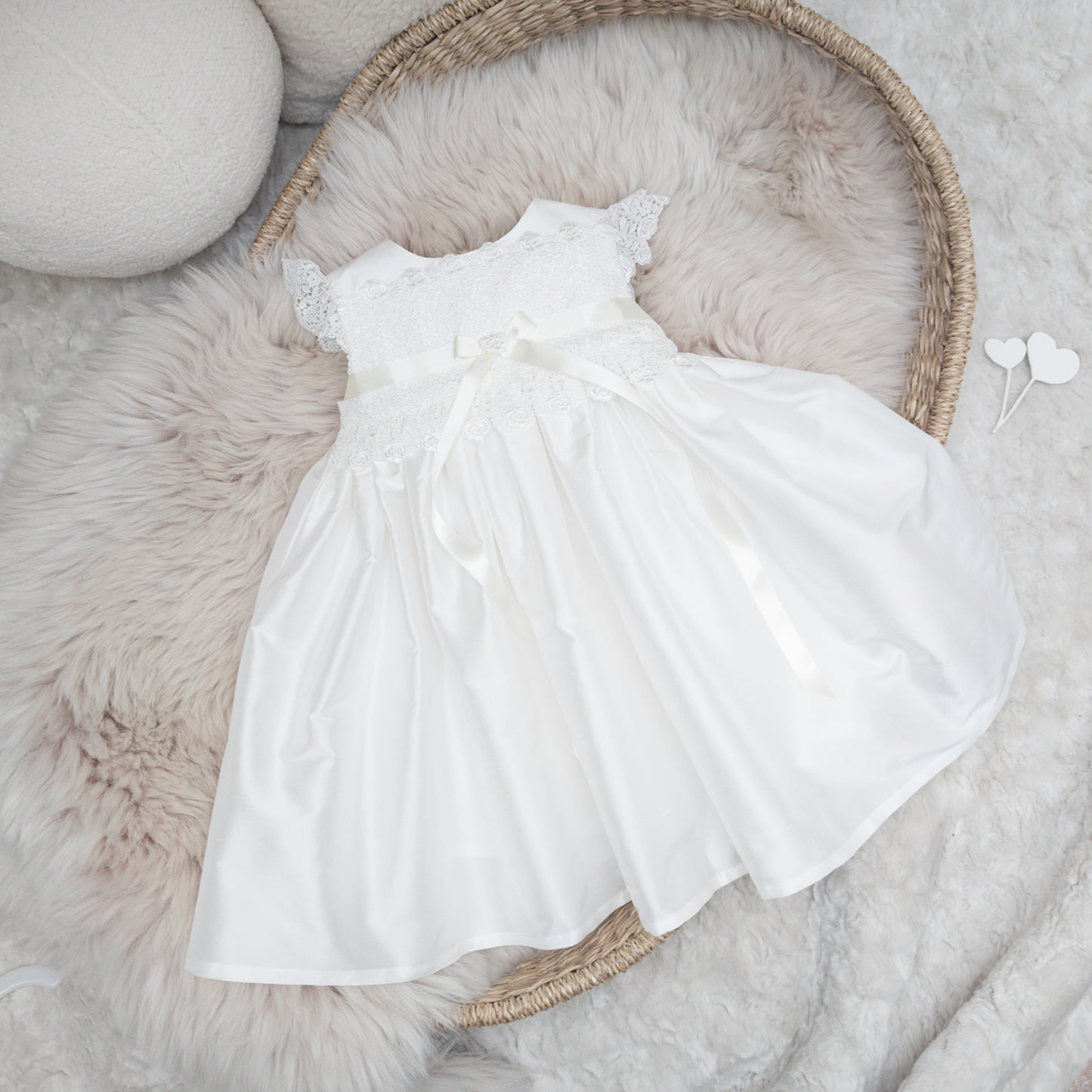 Classic ivory silk Rachel christening dress displayed flatlay on a fluffy backgound