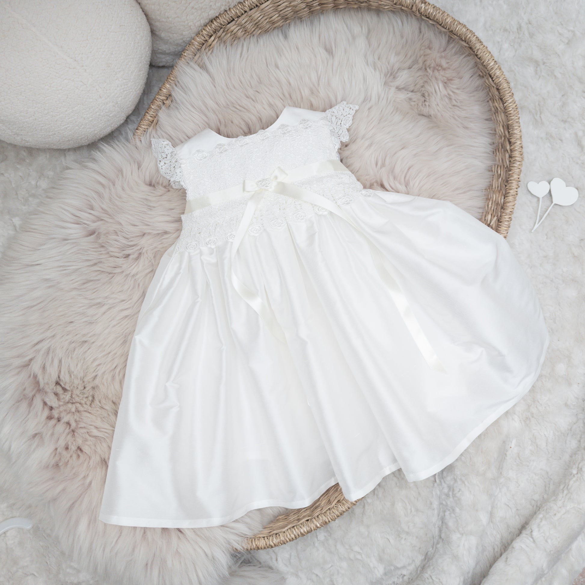 Classic ivory silk Rachel christening dress displayed flatlay on a fluffy backgound