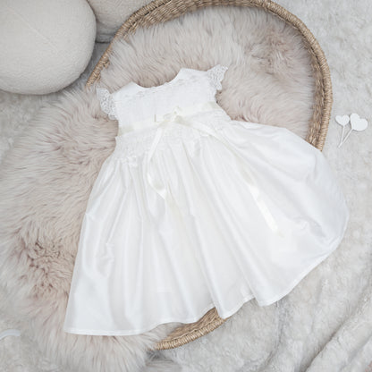 Classic ivory silk Rachel christening dress displayed flatlay on a fluffy backgound