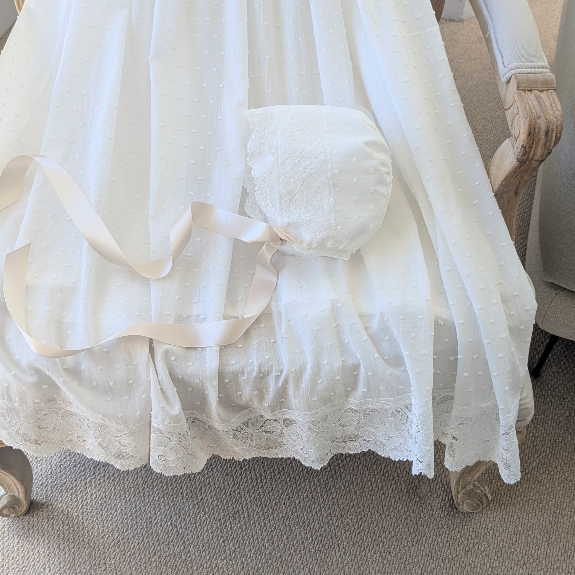 Close up of the wide French lace hem detailing on the bottom of the Eliana christening gown.