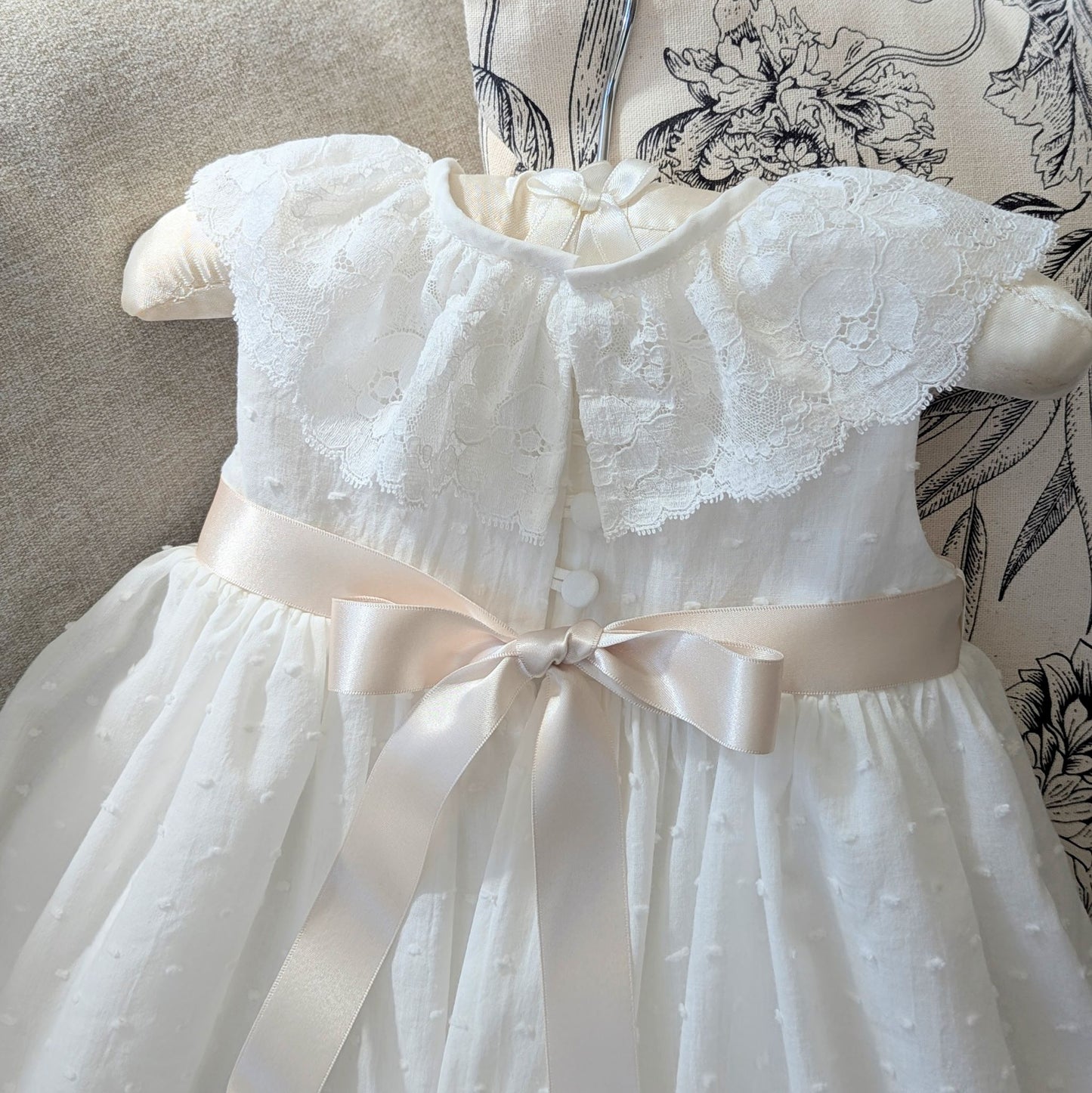 Back closure of the ivory plumetti cotton christening gown featuring six fabric-covered buttons.