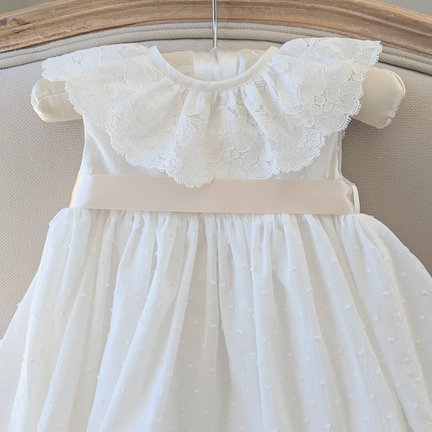 Detail shot of the ivory Swiss dot cotton bodice and darker ivory satin ribbon sash on the Eliana baptism gown.