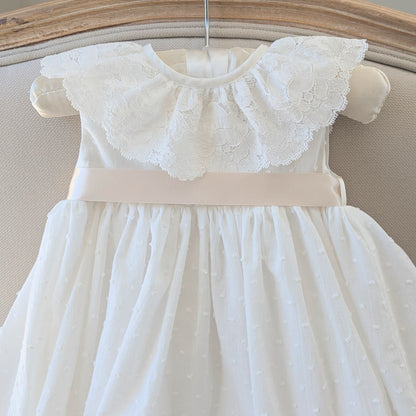 Detail shot of the ivory Swiss dot cotton bodice and darker ivory satin ribbon sash on the Eliana baptism gown.
