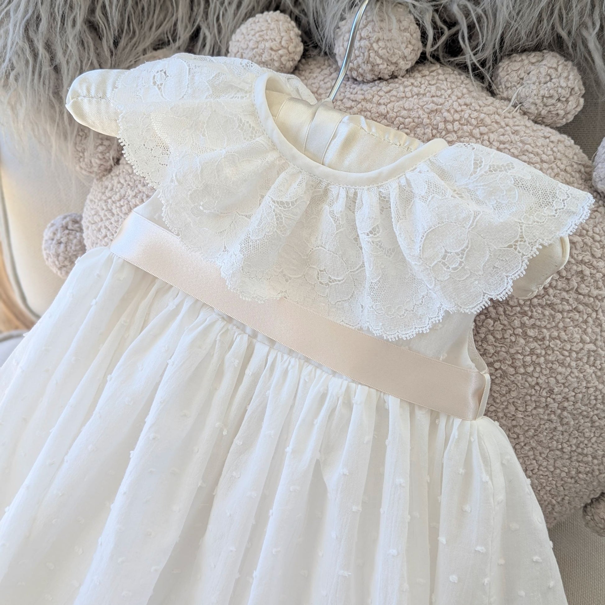 Detail shot of the ivory Swiss dot cotton bodice and darker ivory satin ribbon sash on the Eliana christening gown.