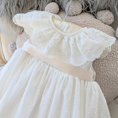 Detail shot of the ivory Swiss dot cotton bodice and darker ivory satin ribbon sash on the Eliana christening gown.
