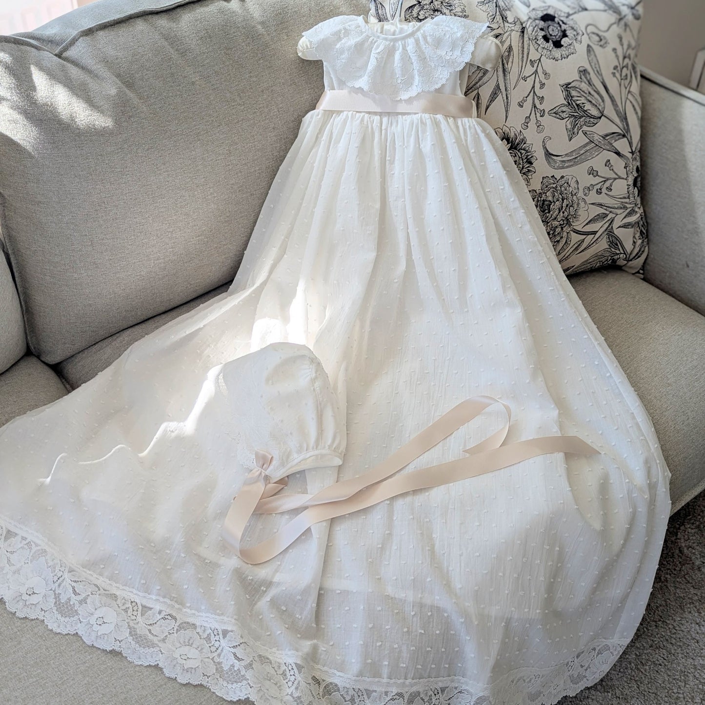 The traditional ivory Eliana christening gown with its matching fully lined cotton bonnet and satin ties.