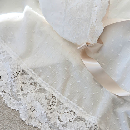 The draped hemline of the long Eliana baptism gown, showcasing the intricate wide French lace.
